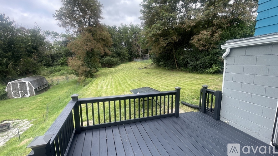 A deck with a black railing overlooks a grassy yard.