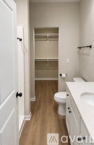 A white bathroom with a toilet, sink and a walk in closet.
