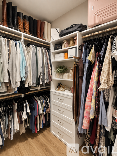 A well organized walk in closet with clothes and drawers.
