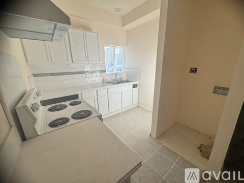 A kitchen with a stove top oven and a tile floor.