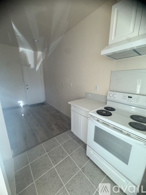 A kitchen with a white stove top oven and white cabinets.