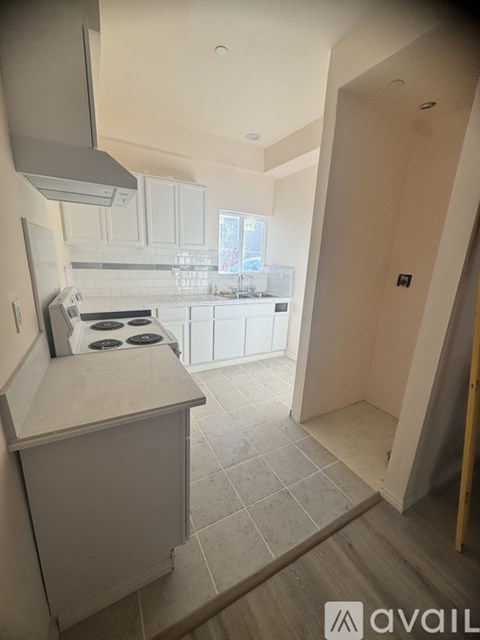 A kitchen with white cabinets and a stove top oven.