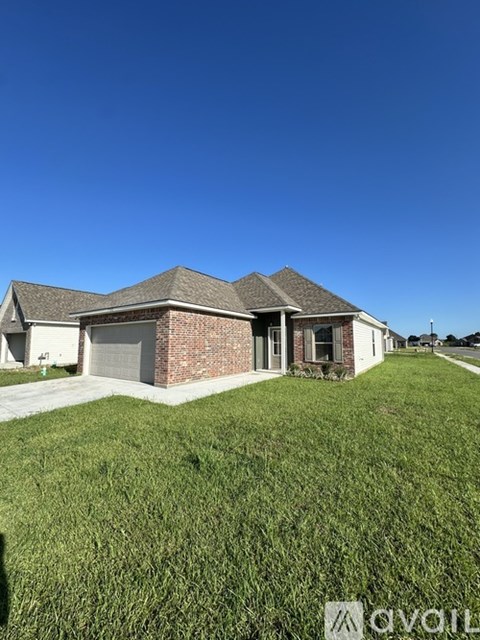 A house with a garage is situated in a grassy area.