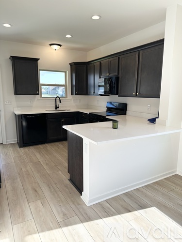 A kitchen with black cabinets and a white island.
