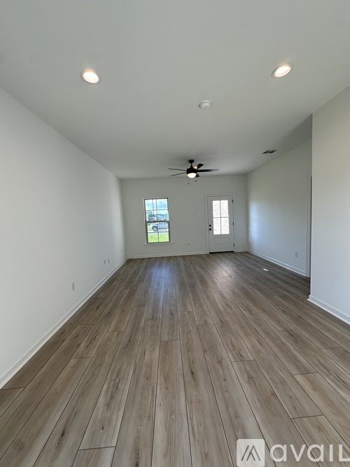A spacious room with wooden flooring and a ceiling fan.