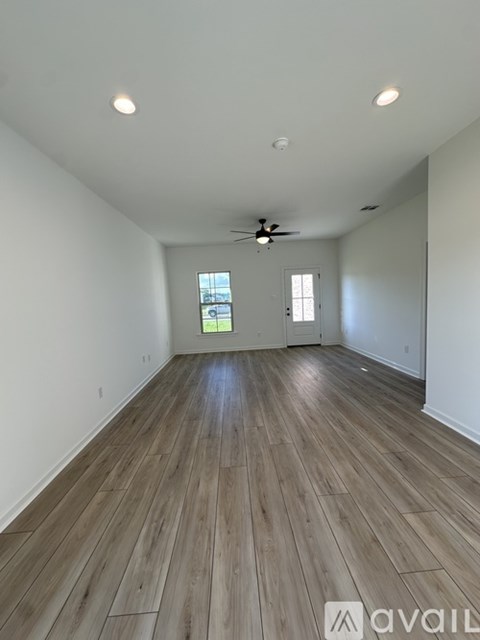 A spacious room with wooden flooring and a ceiling fan.