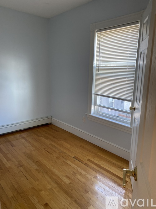 A room with wooden flooring and a window with blinds.