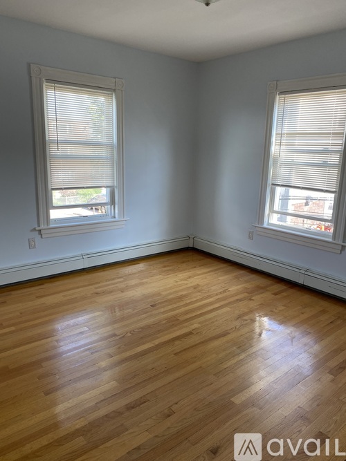 A room with wooden floors and two windows.