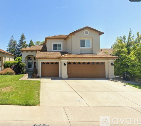 A house with a brown roof and tan walls is for sale.