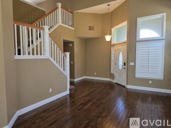 A room with wooden floors and a staircase with white railings.