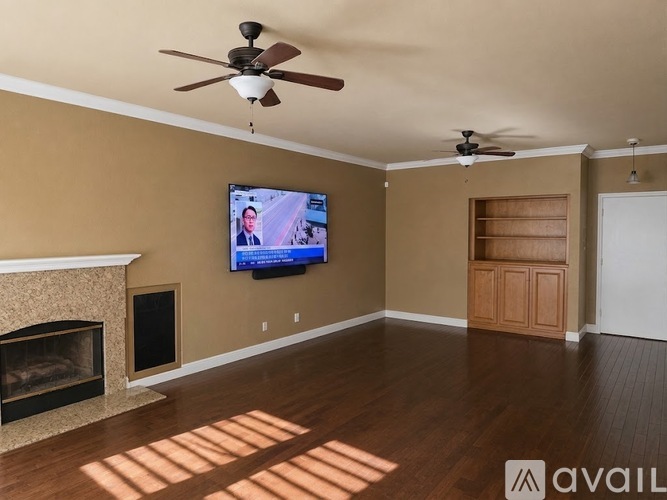 A living room with a fireplace, television, and two ceiling fans.