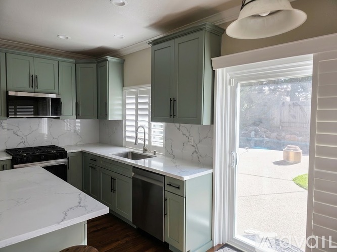 A kitchen with green cabinets and a marble countertop.