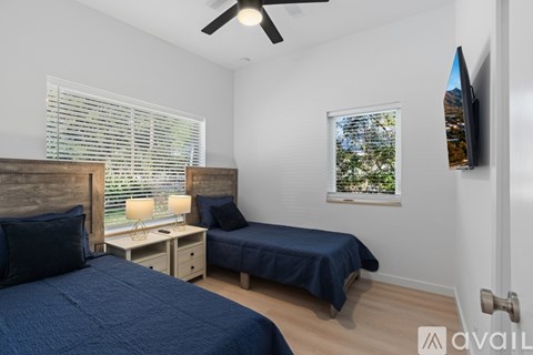 A bedroom with two beds and a ceiling fan.