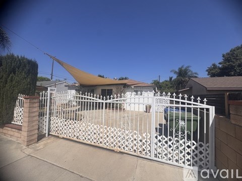 A white fence surrounds a patio with a table and chairs.