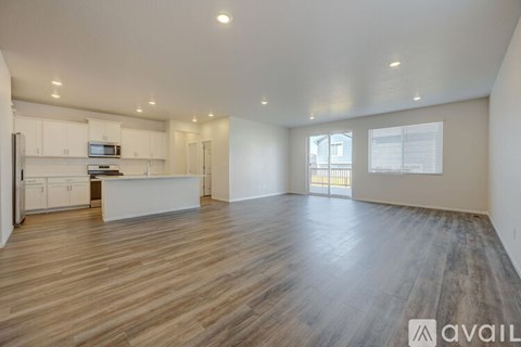 A spacious living room with wooden flooring and white walls.