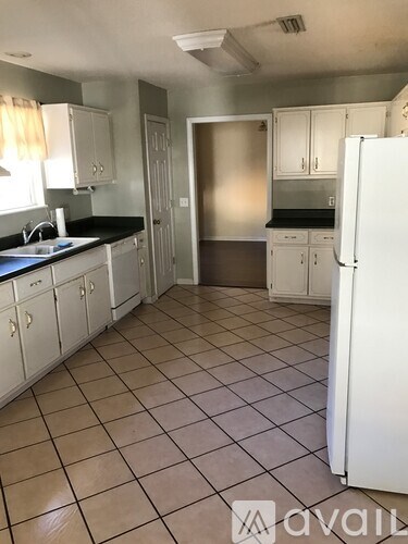 A kitchen with white cabinets and a white refrigerator.