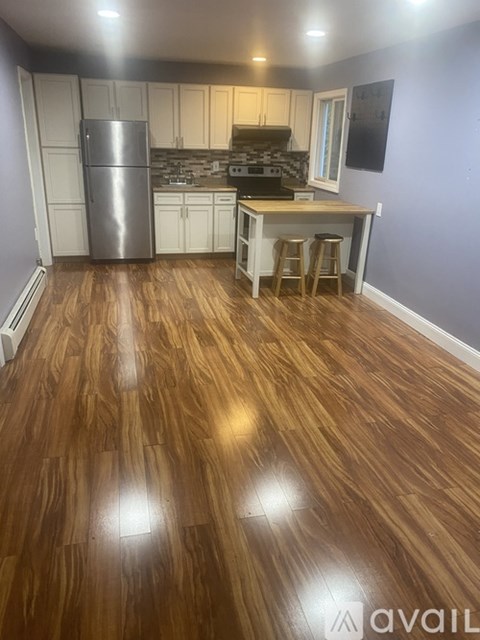 A kitchen with wooden floors and white cabinets.