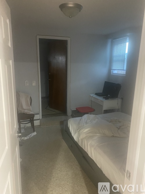 A bedroom with a bed, desk, and chair.