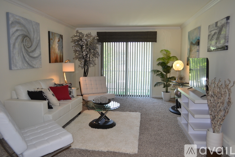 A living room with a white couch, a glass table, and a painting on the wall.