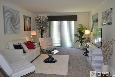 A living room with a white couch, a glass table, and a painting on the wall.