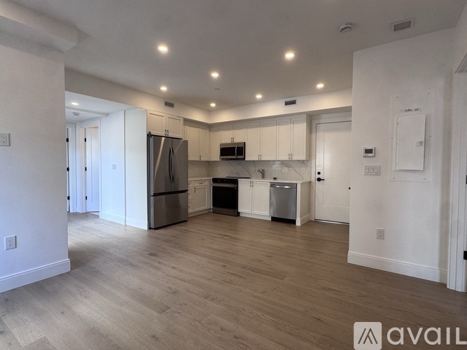 A kitchen with white cabinets and a wooden floor.