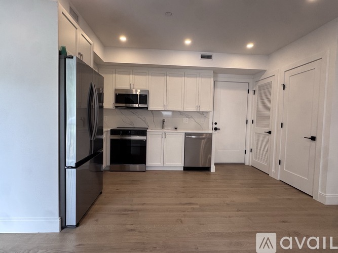 A kitchen with a refrigerator, oven, and a microwave.