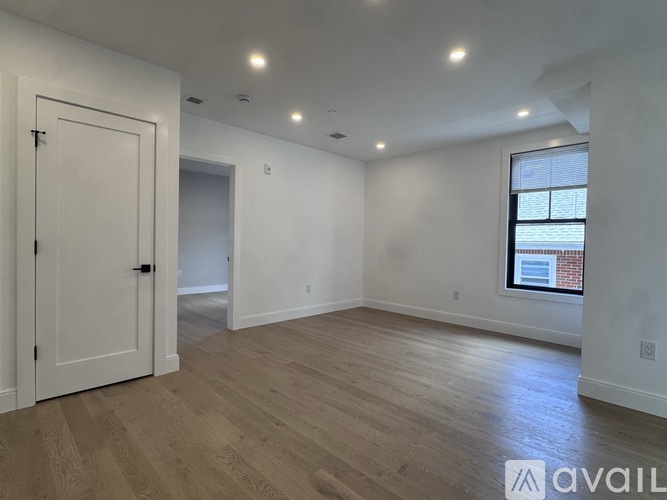 A spacious room with wooden flooring and white walls.