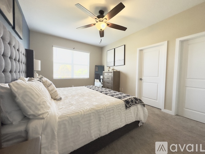 A bedroom with a bed, a ceiling fan, and a nightstand with a lamp.