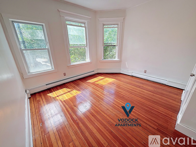 A room with wooden floors and two windows is available for rent.