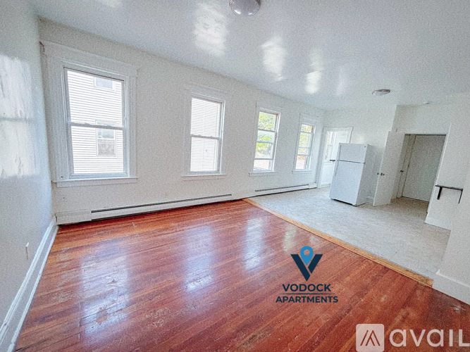 A room with wooden floors and white walls, with a logo for Vodock Apartments on the floor.