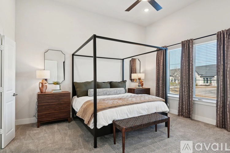 A bedroom with a four poster bed, a nightstand, and a window with curtains.