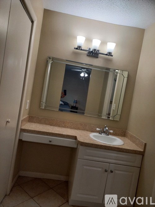 A bathroom with a sink, mirror, and cabinet.