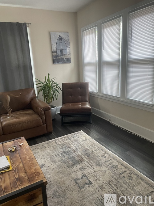 A living room with a brown leather couch, a brown chair, and a rug.