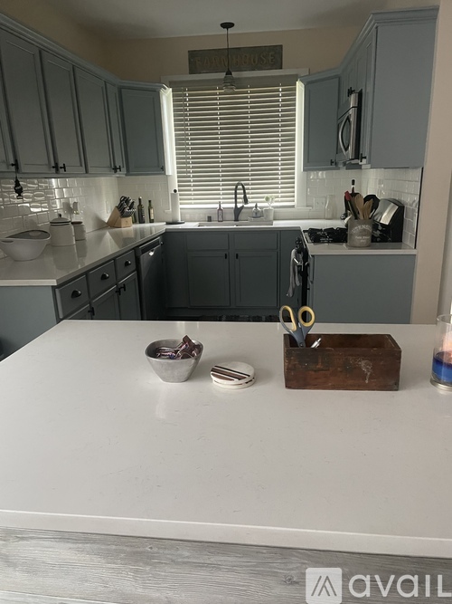 A kitchen with a white counter top and a pair of scissors on it.