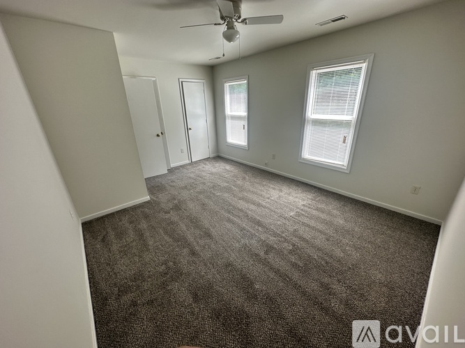 A spacious room with a carpeted floor and a ceiling fan.