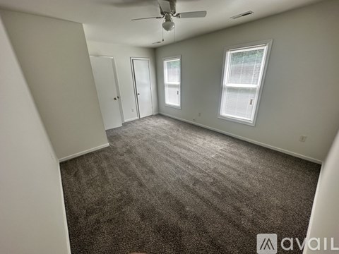 A spacious room with a carpeted floor and a ceiling fan.