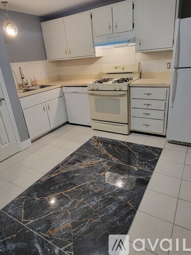A kitchen with a marble floor and white appliances.