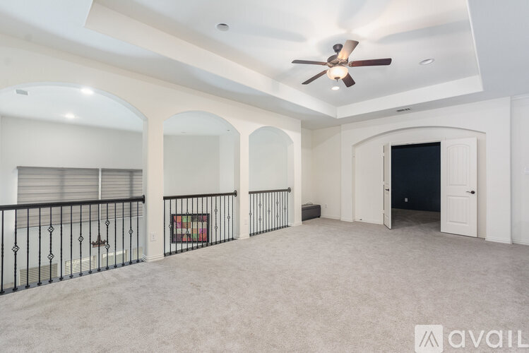 A spacious room with a ceiling fan and a balcony with a railing.