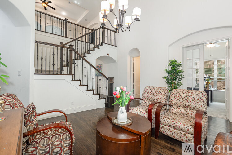 A living room with a couch, chairs, and a staircase.