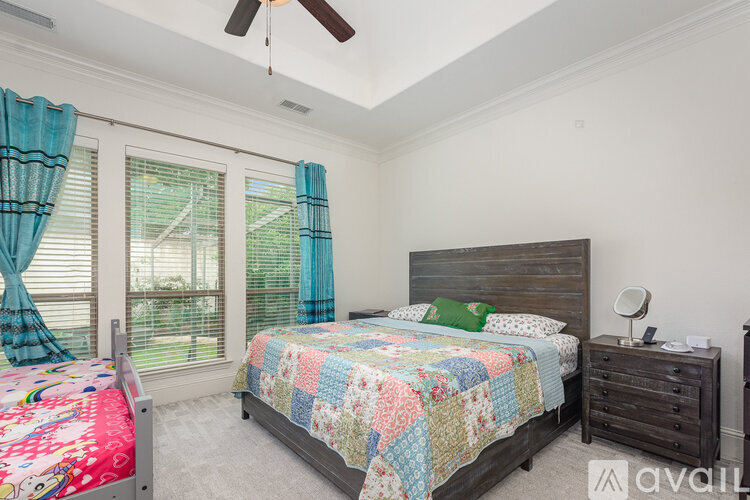 A bedroom with a bed, nightstand, and window with blue curtains.