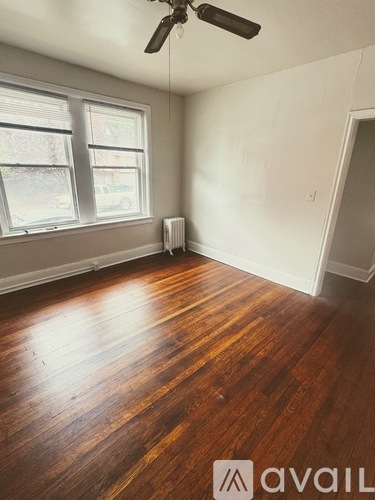 A room with a ceiling fan and wood flooring.