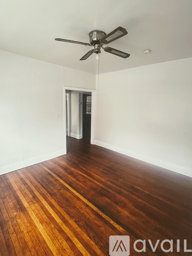 A room with a ceiling fan and wooden flooring.