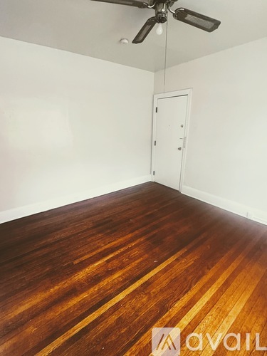 A room with wooden flooring and a ceiling fan.