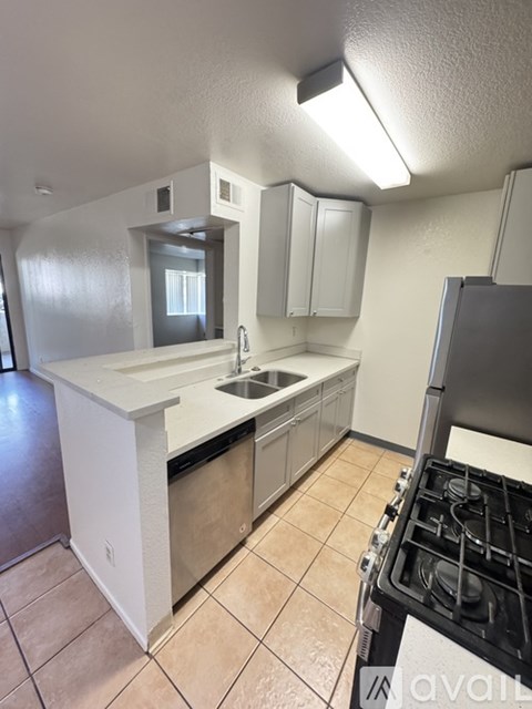 A kitchen with a stove, sink, and cabinets.