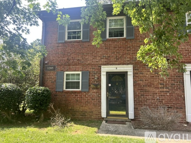 A red brick house with a black door and a small porch.