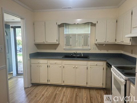 A kitchen with white cabinets and a black countertop.