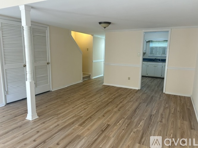 A room with wooden flooring and white columns.