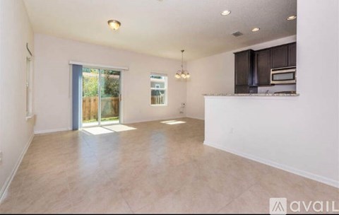 A spacious living room with a kitchenette in the background.