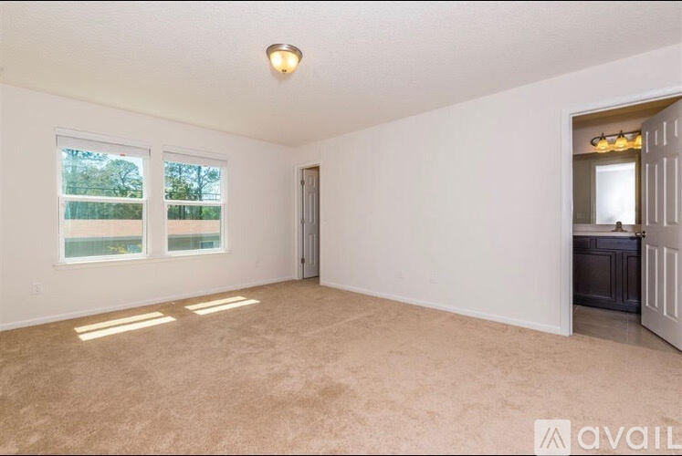 A spacious room with a carpeted floor and a door leading to another room.