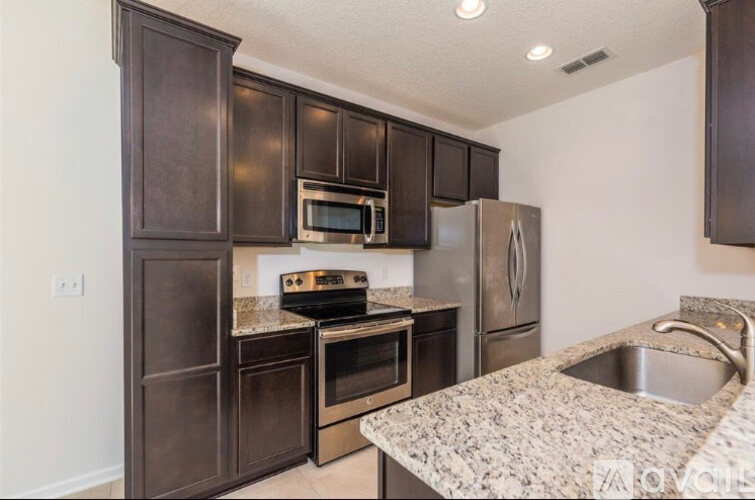 A kitchen with dark brown cabinets and stainless steel appliances.